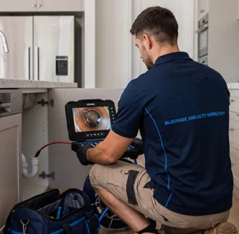 Plumber clearing a blocked toilet in a Earlwood bathroom